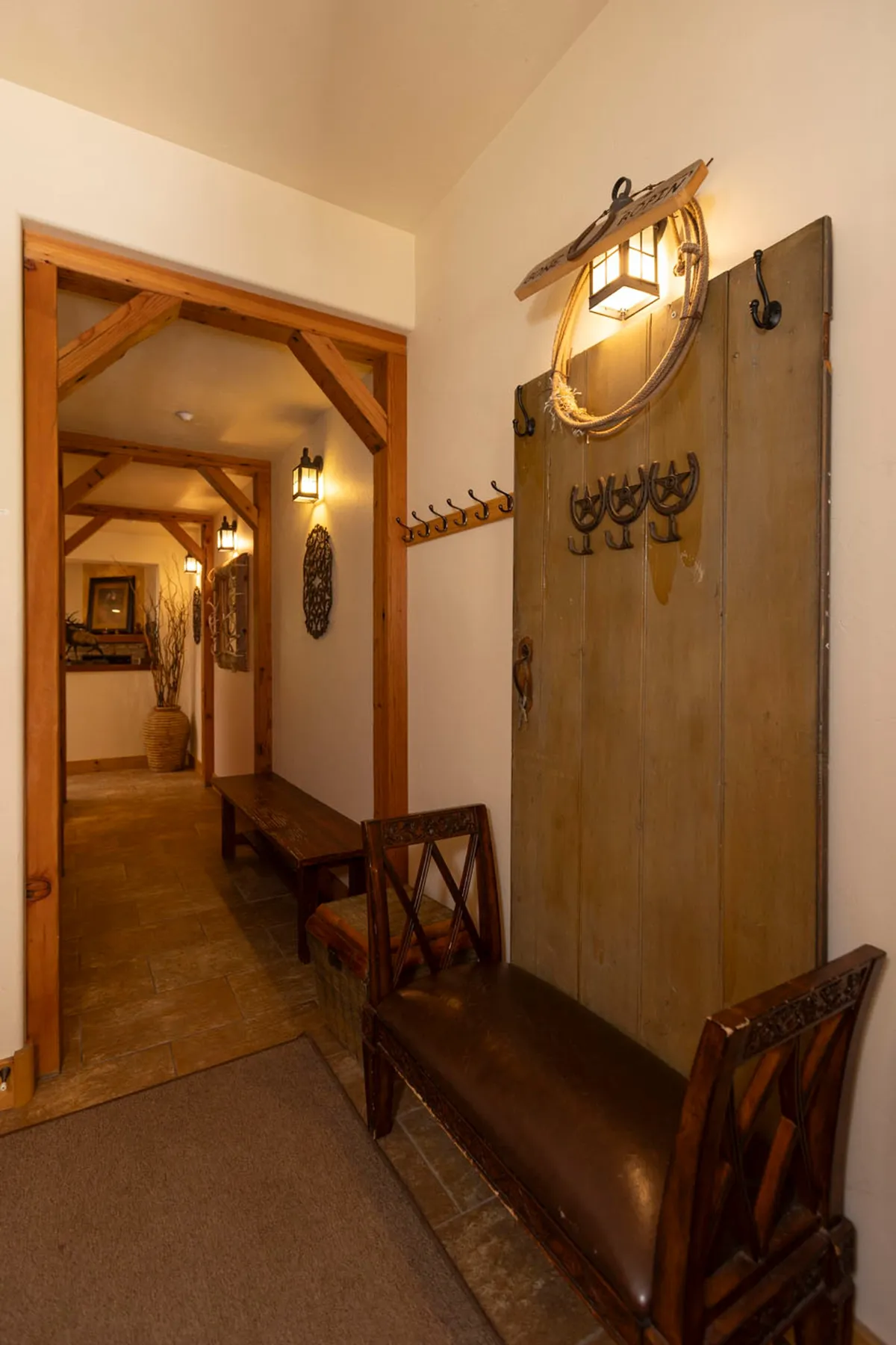A welcoming interior entryway with a wooden coat rack, ornate wall decor, bench seating, and soft lighting. The space evokes warmth and comfort, suggesting a place to gather before or after outdoor adventures, and hints at the transition between inside comfort and mountain exploration.